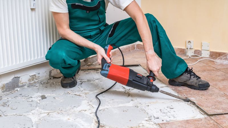 professionnel en train de déposer un carrelage avec un marteau piqueur