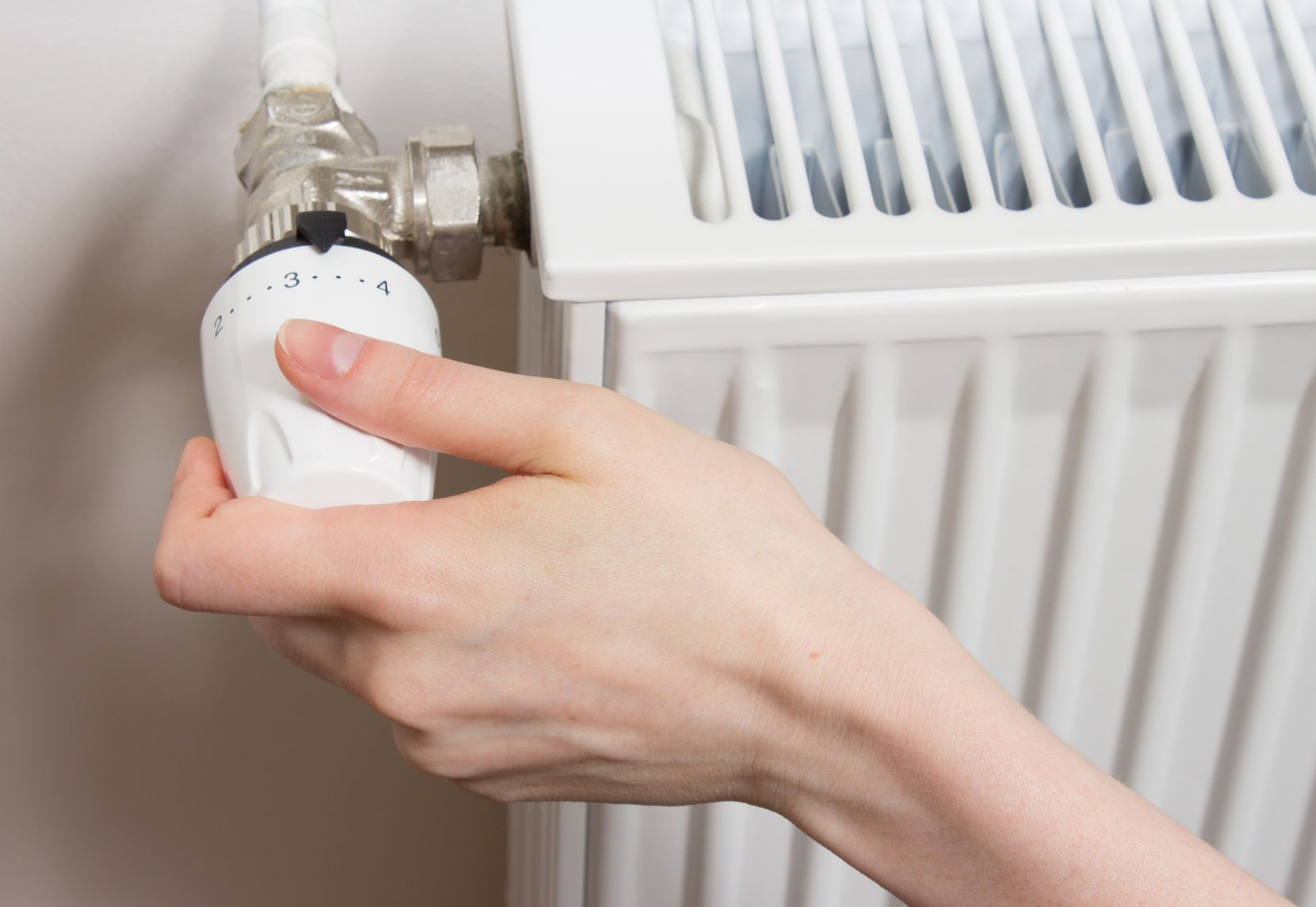 Gros plan sur une main de femme tournant le robinet thermostatique, geste souvent répété quand les radiateurs ne chauffent pas