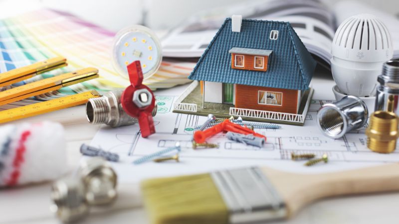 Outils et équipements de plomberie avec une maquette de maison sur un plan, illustrant les coûts de rénovation de plomberie