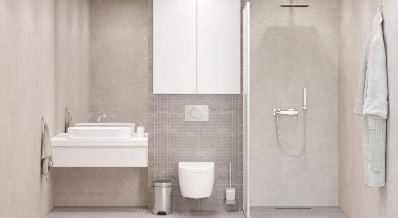 vu de face d une salle de bain rectangulaire beige clair avec un grand miroir rectangulaire au dessus d’un lavabo blanc un meuble de rangement au dessus d un WC suspendu une douche a l italienne avec une cloison vitree un peignoir