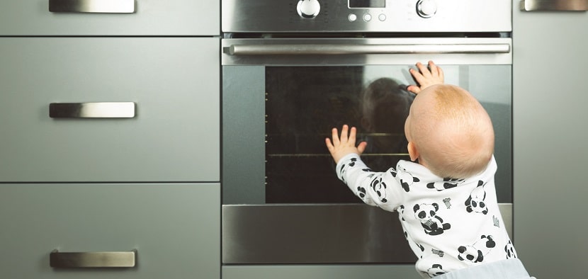 Bébé mettant ses mains sur la porte d'un four à la maison