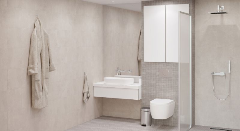 salle de bain rectangulaire beige clair avec un grand miroir rectangulaire au dessus d’un lavabo blanc un meuble de rangement au dessus d un WC suspendu une douche a l italienne avec une cloison vitree un peignoir