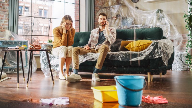 couple dans un appartement avec baches partout gerant au telephone une urgence de fuite