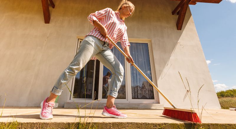 femme qui balaie sa terrasse 