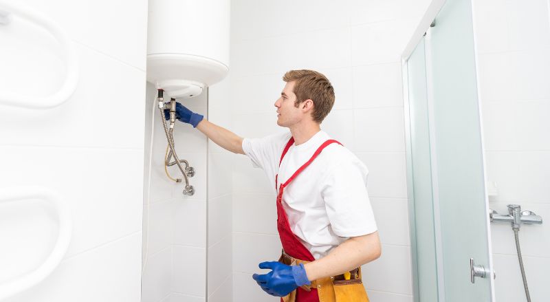 plombier en train d installer un ballon d eau chaude electrique dans une salle de bain