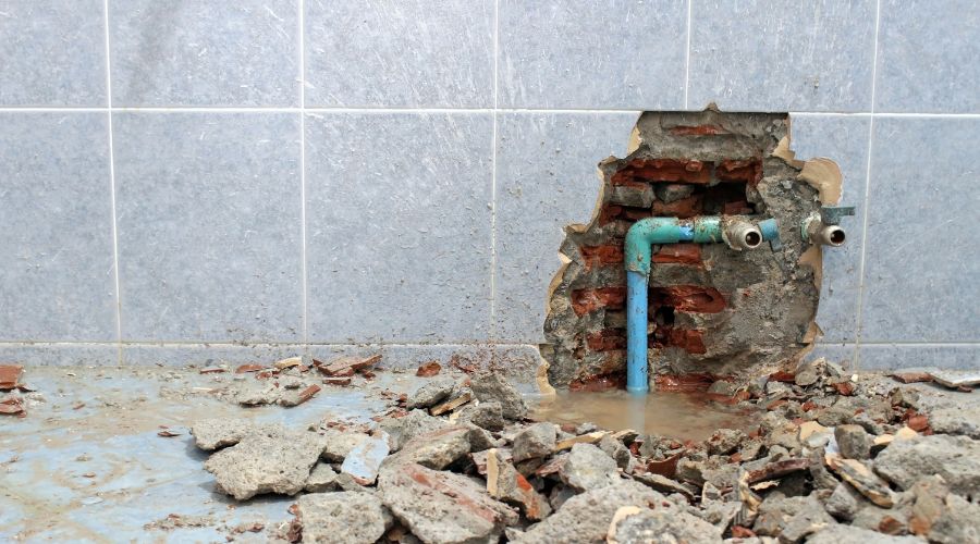 mur carrelé de salle de bain détruit pour accéder à une fuite sur tuyauterie