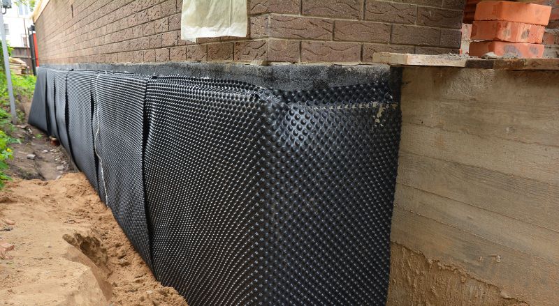 impermeabilisation des fondations de la maison avec installation d une membrane d etancheite alveolee sur le mur exterieur du sous sol d une maison en briques