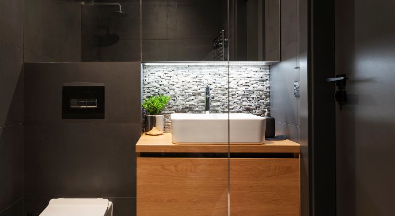 petite salle de bain avec revetement mural noir et meuble sous vasque en bois