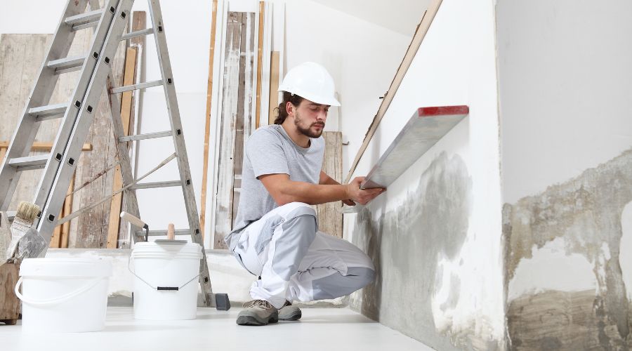 platrier ouvrier dans une maison en chantier de renovation il verifie un mur avec un niveau a bulle 