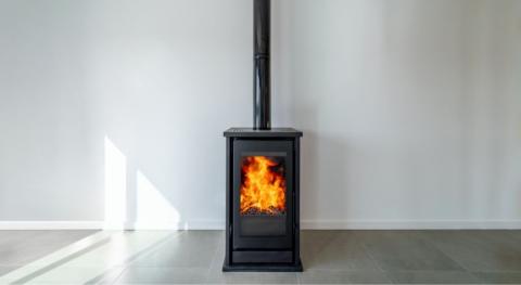 poele a bois avec feu avec flamme brulante derriere la porte vitree l arrivee d air n est pas visible et est sans doute positionnee derriere le poele lui meme