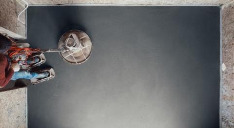 un artisan en train de poncer un beton cire avec une machine