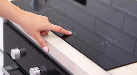 plaque vitroceramique a induction moderne avec quatre zones de cuisson une femme appuie sur la main sur l’écran tactile gros plan