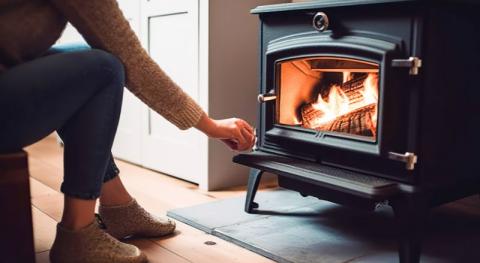 femme refermant la vitre dun poele a bois en marche