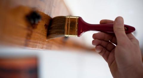 main d homme tenant un pinceau et peignant une poutre en bois