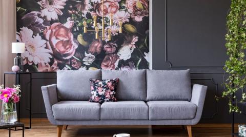 salon avec canape gris papier peint floral rose et gris moulures sur le mur et lampe doree