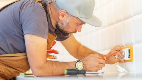 un electricien pose une prise electrique sur une credence de cuisine